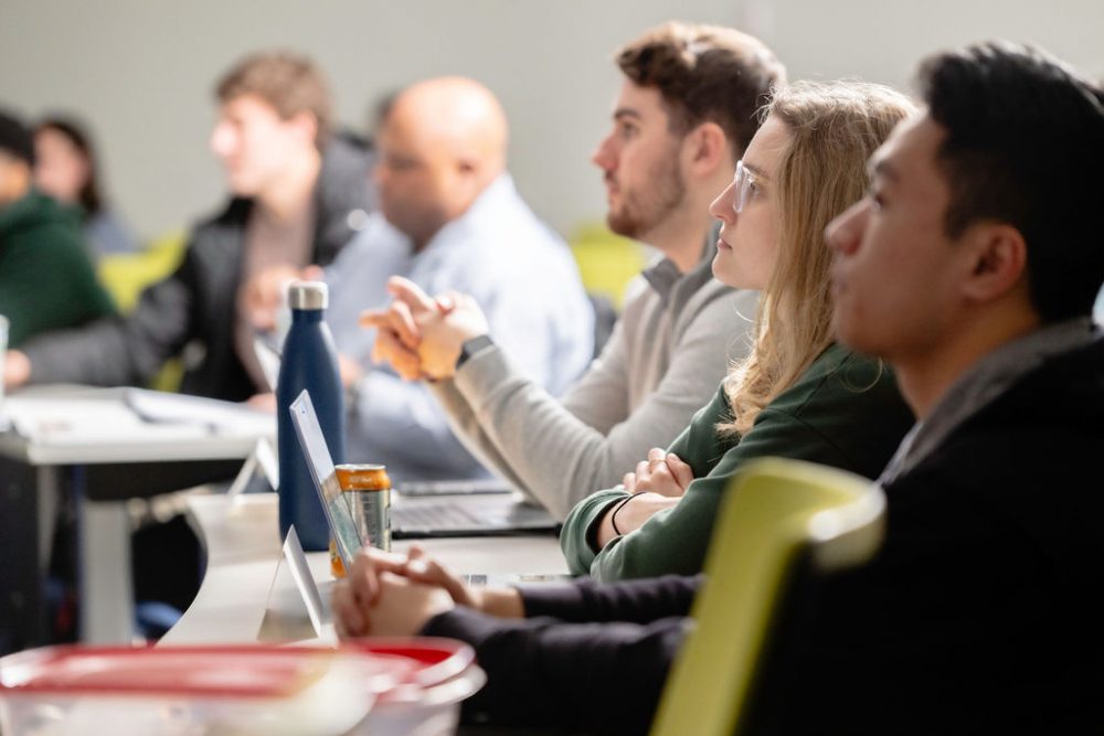 Side view of MBA students in a class engaging with their professor