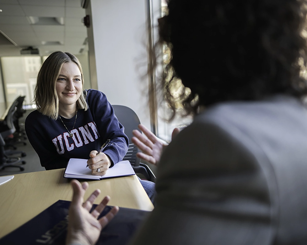 Graduate student seated at a table speaking to a career coach