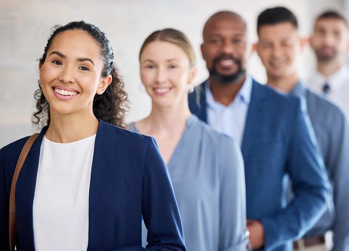A group of five diverse young business professionals standing in a single file line at an office